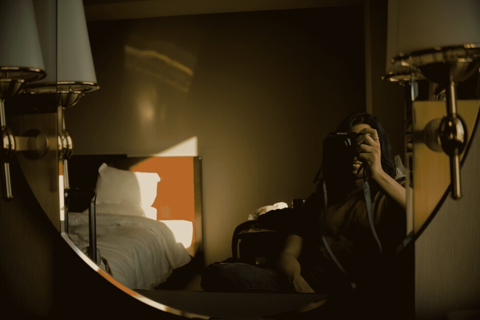 a mirror self-portrait taken by handheld camera in a hotel room