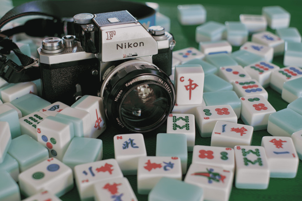 a vintage film camera sits among scattered mahjong tiles